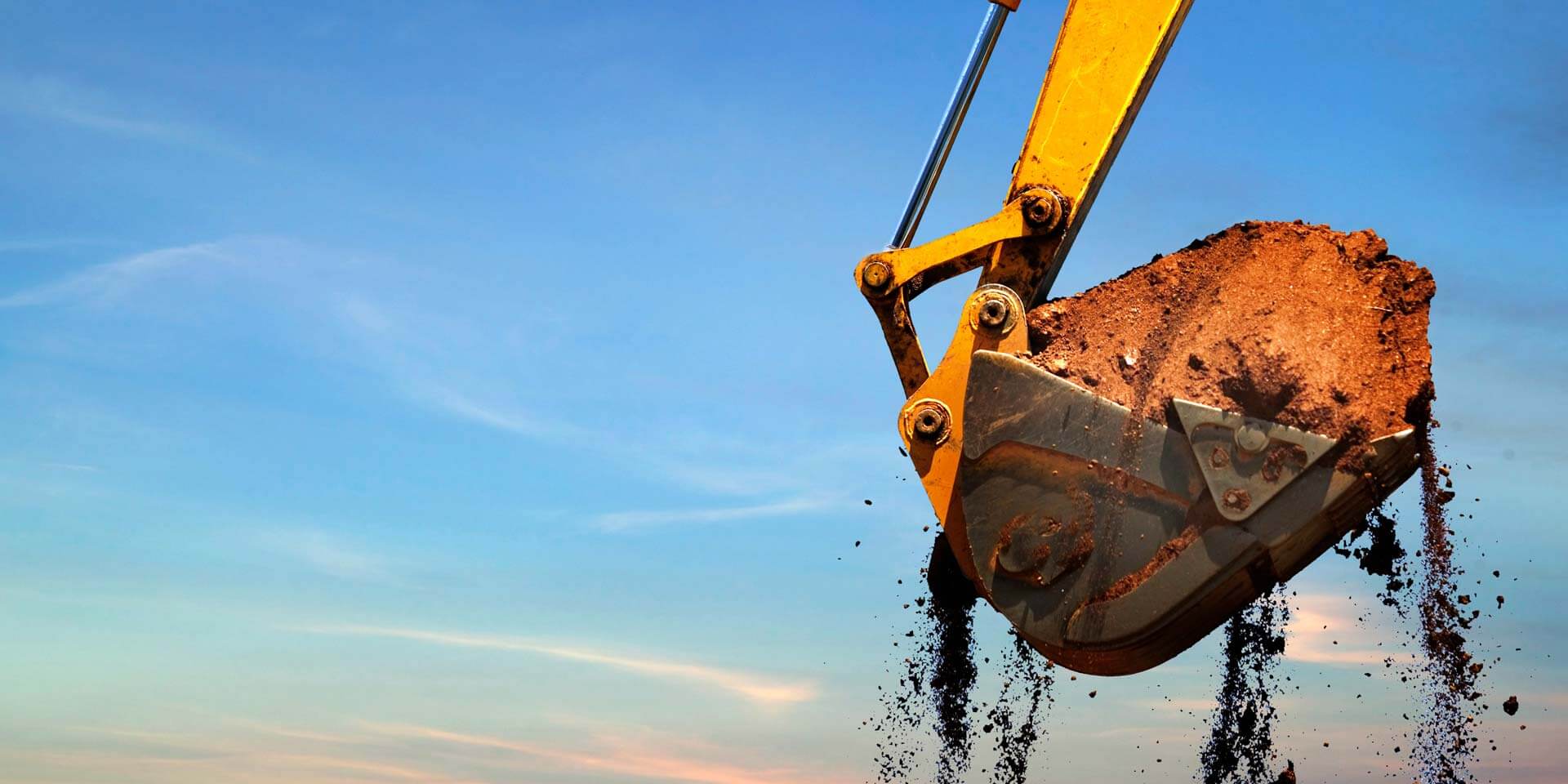 A backhoe is moving dirt at a construction site where a new building that received Commercial Financing is in progress