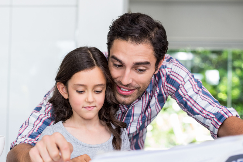 A dad helping his daughter read a book